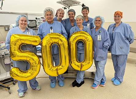 Staff members holding gold balloons that say 500