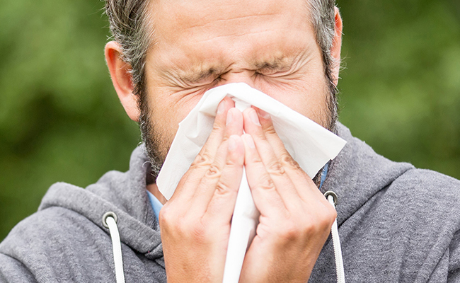 man sneezing into tissue