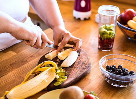 Woman cutting up fruit for smoothie