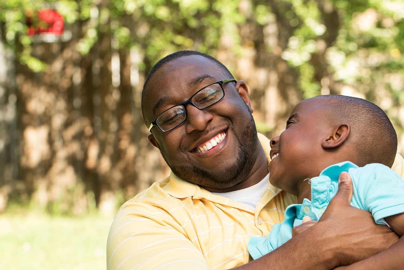 A man under a fruit tree holding his son