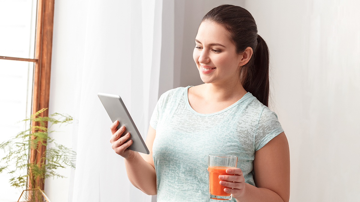 Woman watching her tablet with drink in hand