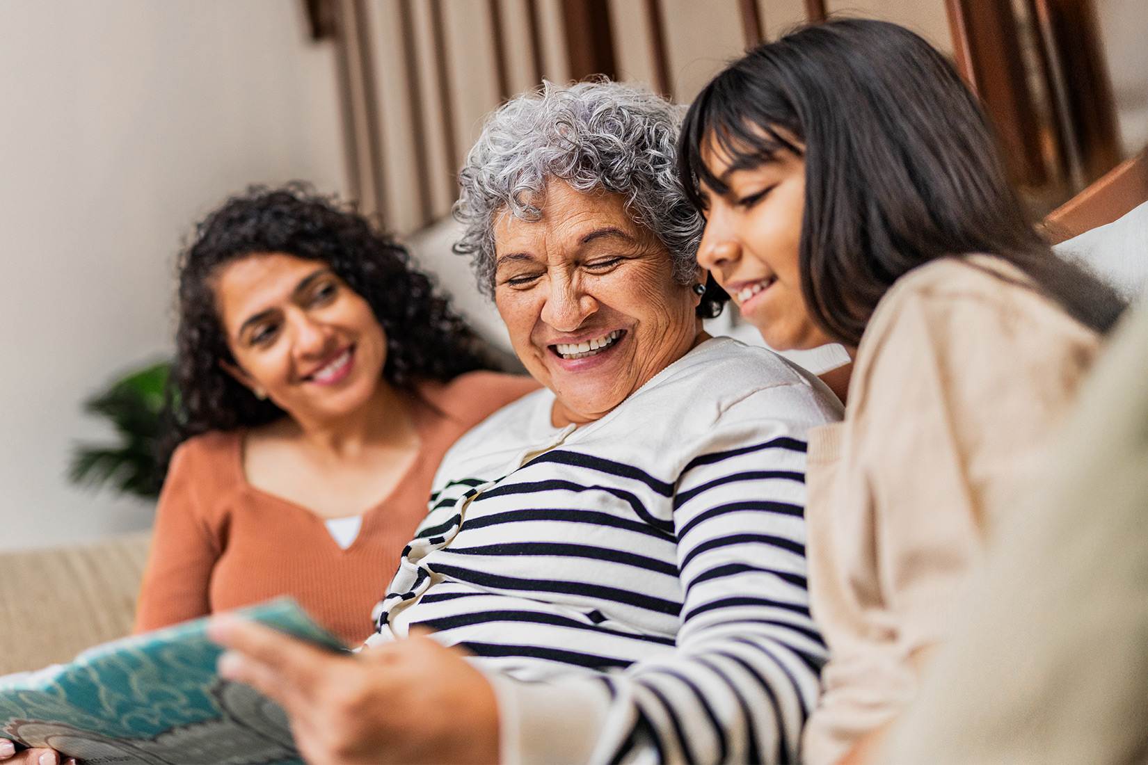 Three generations of women looking at scrapbook on couch