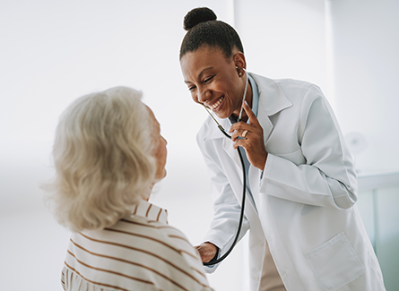 Female doctor checking female patient's heart with stethoscope