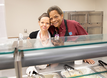 Two employees smiling together in cafeteria