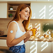Smiling woman in kitchen wearing cgm