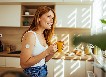 Smiling woman in kitchen wearing cgm