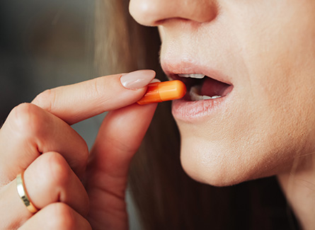 Woman putting an orange capsule in her mouth