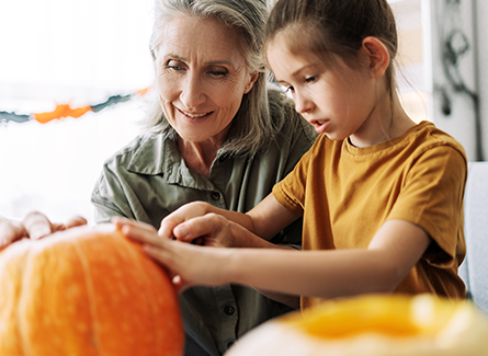 Grandmother carving a pumpkin with granddaughter