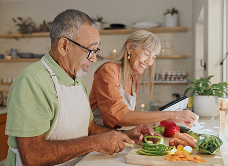 Happy older couple chopping vegetables