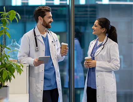 Two doctors talking and smiling while holding coffees