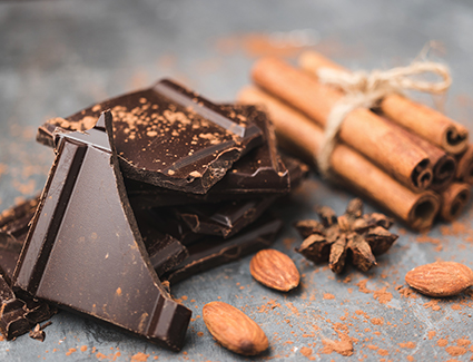 Pile of dark chocolate with cinnamon sticks wrapped in twine