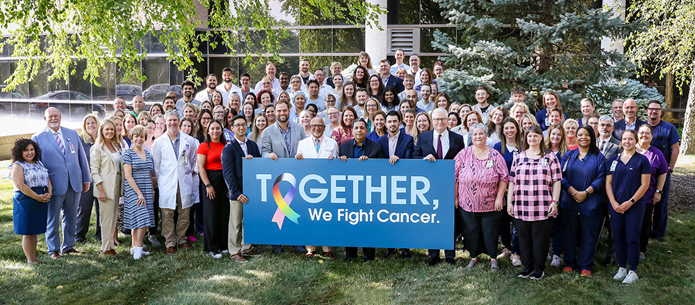 Group photo of cancer care providers with banner that says Together, We Fight Cancer