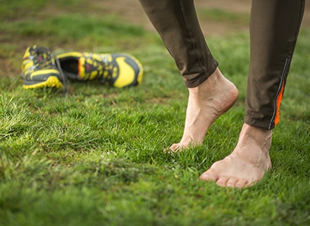 Barefoot man next to empty running shoes in grass