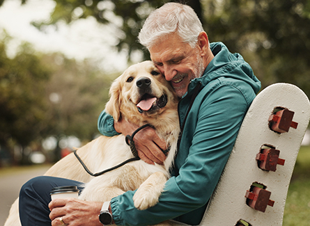 Older man with his golden retriever on bench in park